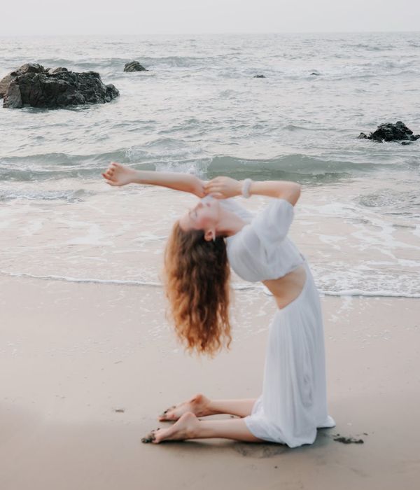 Woman in a calm yoga pose at sunrise, surrounded by warm light.